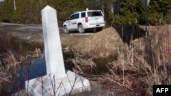 ফাইল ছবি - রক্সহ্যাম সড়কে যুক্তরাষ্ট্র/কানাডা সীমান্ত চিহ্নিতকারী নির্দেশক (২৬ ফেব্রুয়ারি, ২০১৭)