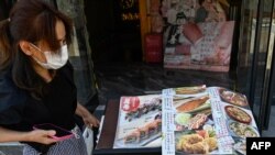 日本驻华大使馆附近的一家日本餐馆前一名女子在看餐馆菜单。（2023年8月29日）