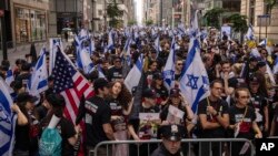 People hold Israeli flags, with one carrying a U.S. flag, as they gather ahead of the annual Israel Day Parade on Fifth Avenue in New York City, June 2, 2024.