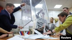 Members of a local electoral commission empty a ballot box, after polling stations closed on the final day of Russia's presidential election, in St. Petersburg, March 17, 2024.