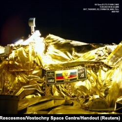 A picture taken from the camera of the lunar landing spacecraft Luna-25 during its flight to the moon shows the mission emblem and the bucket of the lunar manipulator complex, Aug. 15, 2023.