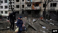 People walk past a damaged residential building following a missile strike in Kyiv on Dec. 13, 2023, amid Russian invasion of Ukraine.