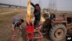 FILE - A man and his grandson prepare to seed farmland in Huangtugang in central China's Henan province on Oct. 23, 2021. China in 2023 is emphasizing the importance of food production with a policy that offers subsidized land reclaimed from manufacturing sites to farmers.
