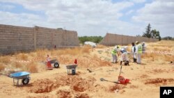 Wafanyakazi wa wizara ya sheria wakichimba eneo linalodhaniwa kuwa kaburi la watu wengi katika mji wa Tarhouna, Libya. Juni 23, 2020. Picha ya AP
