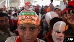 Supporters of the ruling Bharatiya Janata Party (BJP) wear party headwear and cut out masks India's Prime Minister Narendra Modi during an election campaign rally attended by Modi in Prayagraj on May 21, 2024.