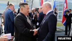 Pemimpin Korea Utara Kim Jong Un berjabat tangan dengan Presiden Rusia Vladimir Putin di fasilitas peluncuran roket Kosmodrom Vostochny di Oblast Amur, Rusia Timur Jauh, 13 September 2023 dalam gambar yang dirilis oleh Kantor Berita Korea Utara (KCNA).