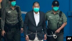 FILE - Jimmy Lai is escorted by Correctional Services officers to get on a prison van before appearing in a court in Hong Kong, Dec. 12, 2020.