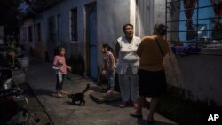 Eglisa Arias, center, talks outside the home she is renting in Frontera in the state of Tabasco, Mexico, Nov. 29, 2023. Arias was driven from her home when a fast-moving sea-level rise destroyed her coastal community of El Bosque.