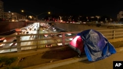 FILE - A tarp covers a portion of a homeless person's tent on a bridge overlooking the 101 Freeway in Los Angeles, Feb. 2, 2023. The United States experienced a dramatic 12% increase in homelessness, federal officials said on Dec. 15, 2023. 