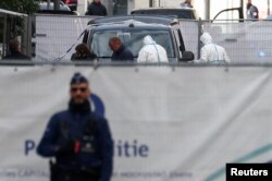 Policajac stražari ispred forenzičara koji prikupljaju dokaze nakon smrtonosne pucnjave u Briselu, Belgija, 17. oktobra 2023.