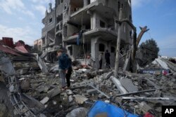 Palestinians inspect the rubble of a building of the Al Nawasrah family destroyed in an Israeli strike in Maghazi refugee camp, central Gaza Strip, Dec. 25, 2023.