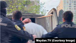 "Meclis.info"nun rəhbəri İmran Əliyev barəsində həbs qətimkan tədbiri seçildikdən sonra polis maşınına mindirilərkən. (19 aprel 2024-cü il)