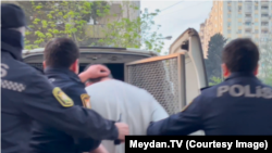 "Meclis.info"nun rəhbəri İmran Əliyev barəsində həbs qətimkan tədbiri seçildikdən sonra polis maşınına mindirilərkən. (19 aprel 2024-cü il)