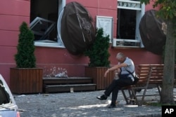 A man sits next to a restaurant damaged by a Russian attack in Chernihiv, Ukraine, Aug. 19, 2023.