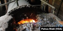 Proses pembakaran limbah plastik pada tungku pabrik tahu milik Gufron (foto Petrus Riski-VOA)