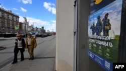 A poster promoting contract army service and reading "Our job, defending the homeland" adorns the door of a shop, with the U.S. embassy seen on the left, in central Moscow on April 22, 2023.