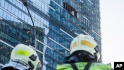 Petugas pemadam kebakaran berdiri di samping bangunan yang rusak di kawasan bisnis "Kota Moskow" setelah dilaporkan terjadi serangan pesawat tak berawak di Moskow, Rusia, Selasa dini hari, 1 Agustus 2023. (Foto: AP)