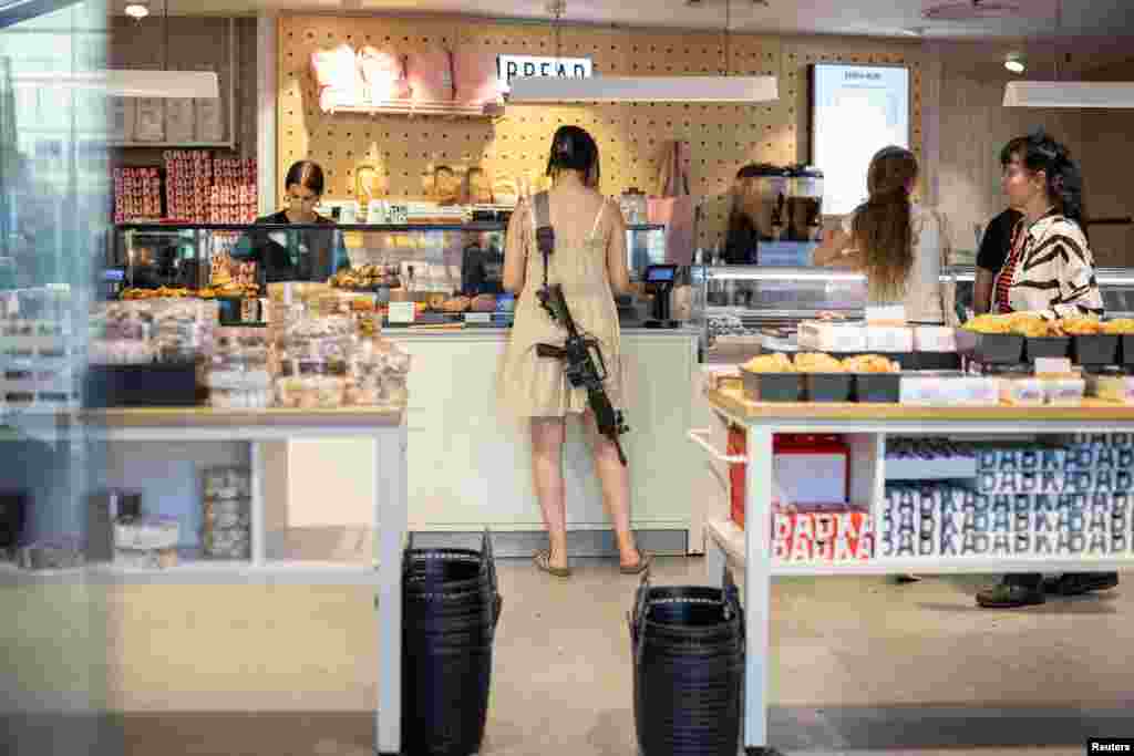 A woman with a rifle shops in a bakery in Tel Aviv, Israel, amid the ongoing conflict between Israel and Hamas, June 4, 2024.
