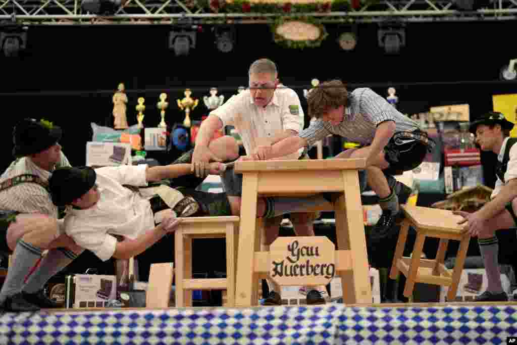 Men dressed in traditional clothes try to pull the opponent over the table at the German Championships in Fingerhakeln or finger wrestling, in Bernbeuren, Germany, May 12, 2024. 