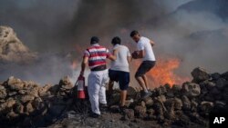 FILE - Local residents try to extinguish a fire, near the seaside resort of Lindos, on the Aegean Sea island of Rhodes, southeastern Greece, on July 24, 2023.
