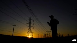 A jogger passes under power lines during an evening run in San Antonio, Texas, June 26, 2023. Meteorologists say scorching temperatures brought on by a heat dome have taxed the Texas power grid and threaten to bring record highs to the state.