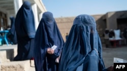 FILE - Afghan women wait for food in the Baraki Barak district of Logar province, Jan. 7, 2024. A United Nations report released in December said the Taliban are sending to prison women who complain to them about gender-based violence and do not have male relatives to stay with.