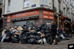 FILE - A man walks past piles of garbage in Paris, March 13, 2023.