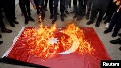 Sejumlah demonstran di Mosul, Iraq, membakar bendera Turki dalam aksi protes terhadap serangan Turki ke wilayah Dohuk, Irak, pada 21 Juli 2022. (Foto: Reuters/Khalid Al-Mousily)