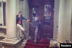 Demonstranti upotrebljavaju motke kako bi razbili prozore na glavnom ulazu u Skupštinu Grada Beograda, tokom protesta opozicije i građana zbog izbornih neregularnosti, u Beogradu, 24. decembra 2023. (Foto: Reuters)