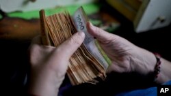 ພະ​ນັກ​ງານ​ຄົນ​ນຶ່ງ​ນັບ​ເງິນ​ຢູ່​ຮ້ານ​ຊຸບ​ເປີ​ມາ​ເກັດ​ແຫ່ງ​ນຶ່ງ​ໃນ​ນະ​ຄອນຫຼວງ ບູ​ເອ​ນອ​ສ ແອ​ເຣັ​ສ, ອາ​ເຈັນ​ຕີ​ນາ, 21 ພະ​ຈິກ 2023.