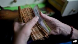 FILE - A worker counts money at a grocery store in Buenos Aires, Argentina, Nov. 21, 2023.