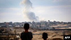Boys watch smoke billowing during Israeli strikes east of Rafah in the southern Gaza Strip on May 13, 2024.