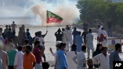 FILE - Supporters of Pakistan's former Prime Minister Imran Khan block a road as police fire tear gas to disperse them during a protest in support of Khan in Karachi, Pakistan, May 9, 2023.