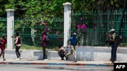 FILE - A man runs after hearing gunshots near the National Palace in Port-au-Prince, Haiti, April 2, 2024. The next day, armed gangs looted Haiti's National Library.