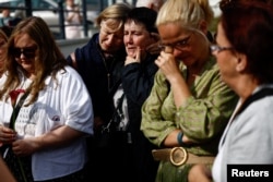 People react as fans gather outside late Irish singer Sinead O'Connor's former home to say their last goodbye to her on the day of her funeral procession, in Bray, Ireland, Aug. 8, 2023.