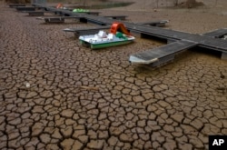 FILE - A pedal boat is tied to a dock in a dried part of the Sau reservoir, about 100 km (62 miles) north of Barcelona, Spain, April 18, 2023.