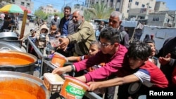 Palestinians gather to receive food cooked by a charity kitchen, amid shortages of aid supplies, after Israeli forces launched a ground and air operation in the eastern part of Rafah in the southern Gaza Strip, May 8, 2024.