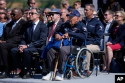 D-Day veteran John Wardell, right, sits in the front row next to U.S. Secretary of State Antony Blinken, center, and Secretary of Defense Lloyd Austin, left, as President Joe Biden speaks next to the Pointe du Hoc monument in Normandy, France, June 7, 2024.