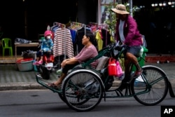 រូបឯកសារ៖ ស្ត្រីម្នាក់ធ្វើដំណើរតាមស៊ីក្លូនៅផ្សារមួយ ក្នុងរាជធានីភ្នំពេញ កាលពីថ្ងៃទី ១០ ខែវិច្ឆិកា ឆ្នាំ ២០២២។