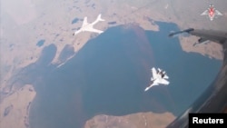 资料照片：俄罗斯国防部公布的视频截图显示，在俄罗斯和中国军机在美国阿拉斯加州附近联合巡航期间，一架中国军队的轰6-K型轰炸机在一架俄军苏-30CM战斗机的伴随下飞行。(2024年7月25日)