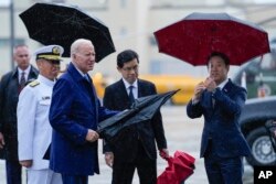President Joe Biden holds an umbrella as he stands in the rain after disembarking from Air Force One at Marine Corps Air Station Iwakuni in Iwakuni, Japan, May 18, 2023.