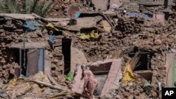 A woman tries to recover some of her possessions from her home which was damaged by the earthquake in the village of Tafeghaghte, near Marrakech, Morocco, Sept. 11, 2023. 