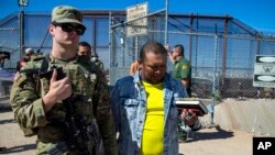 Tentara Amerika Serikat mengawal para migran untuk diproses oleh pihak imigrasi setelah memasuki wilayah El Paso, Texas dari Ciudad Juarez, Meksiko, 10 Mei 2023. (Foto: Andres Leighton/AP Photo, File)
