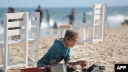 Палестинска девојка мие прибор на плажа во Деир ел-Балах, во центарот на Појасот Газа, на 24 мај 2024 година.