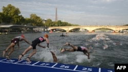 Sejumlah atlet triathlon terjun ke Sungai Seine dengan Menara Eiffel sebagai latar belakang dalam acara Tes Olimpiade Triathlon Dunia 2023 putra di Paris, 18 Agustus 2023. (Foto: AFP)