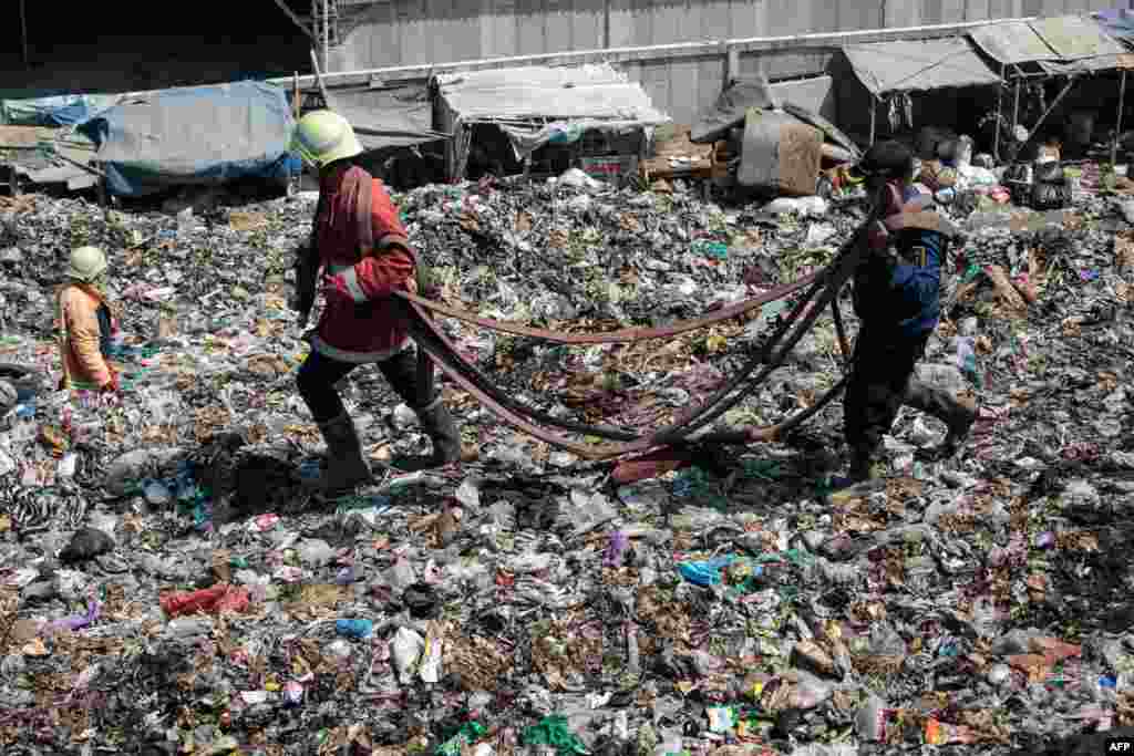 Firefighters carry a water hose as they try to extinguish a fire that has been burning for four days at the Putri Cempo landfill in Solo, Central Java, Indonesia.