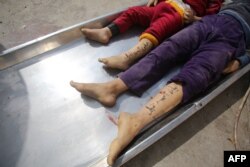 Jenazah anak-anak dari keluarga Nateel, dengan nama Hani (Kiri) dan Layan ditulis di kaki mereka oleh orang tuanya untuk membantu identifikasi, di kamar mayat rumah sakit di Deir el-Balah, 22 Oktober 2023. (Bashar TALEB / AFP)