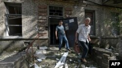 Local residents leave a destroyed residential building after a missile attack in Lugansk, Russian-controlled Ukraine, June 7, 2024.
