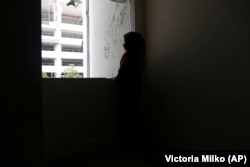 Pengantin anak Rohingya, R, usia 14 tahun, berdiri di samping jendela di lorong kompleks apartemen di Kuala Lumpur, Malaysia, pada 5 Oktober 2023. (AP Photo/Victoria Milko)