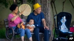 资料照片：北京公园里一对老夫妇和一名幼儿在乘凉。（2023年6月29日）
